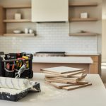 "Renovation tools and blank material sample boards on a kitchen countertop in a bright modern home interior with updated tile and fresh paint setup."