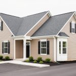 Front exterior of a single-family home with a visible bump-out addition and matching windows and siding under a bright overcast sky.